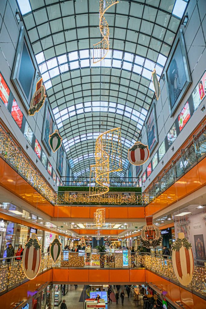 A vibrant shopping mall adorned with holiday lights and decorations during Christmas season.